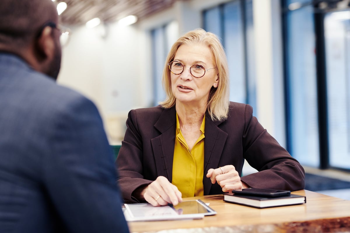 Professional mature lawyer sitting at the table and talking to the man, they discussing business during meeting