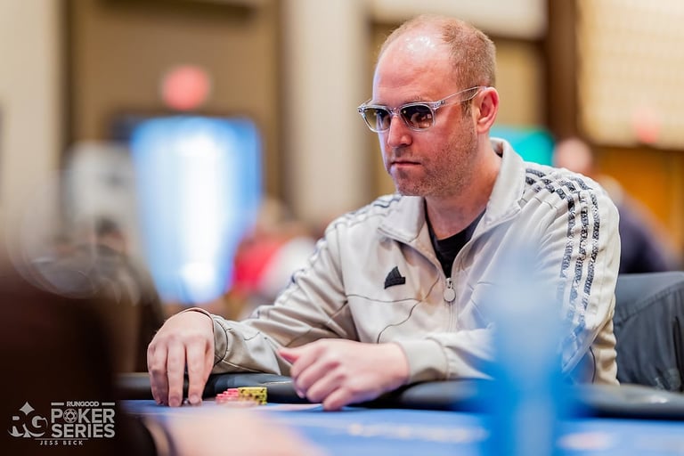 Man wearing sunglasses and beige jacket at poker table during tournament